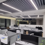 Modern open-plan office with acoustic ceiling baffles and integrated lighting to improve sound control and workplace comfort