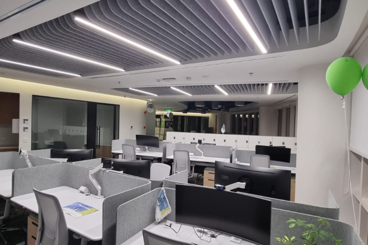 Modern open-plan office with acoustic ceiling baffles and integrated lighting to improve sound control and workplace comfort