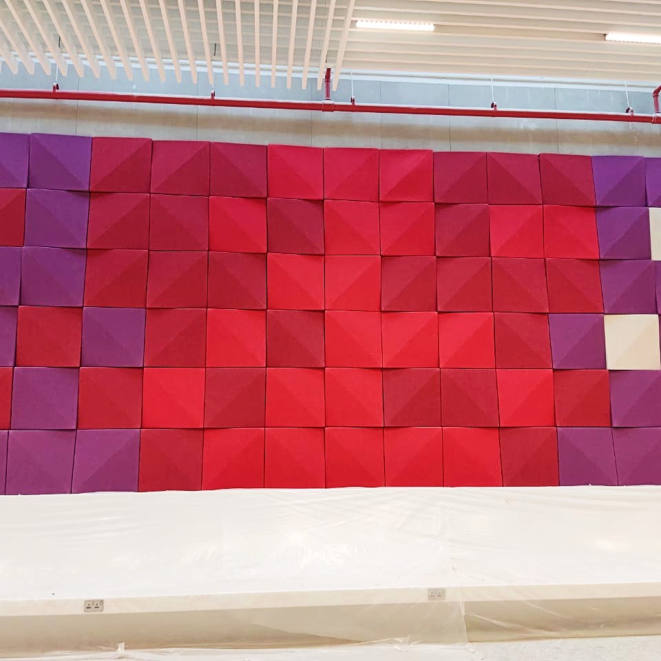 Custom-coloured acoustic 3D panels forming a decorative backdrop in lobby area