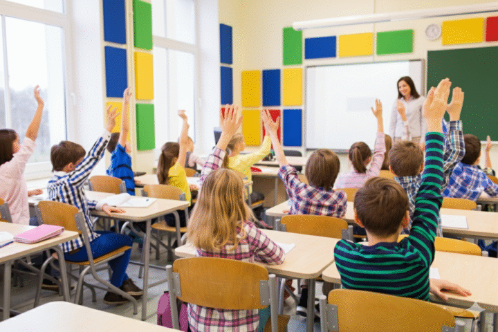 Students raising their hands in a classroom with colourful Decrasound polyester acoustic panels on the walls, improving sound clarity and focus.