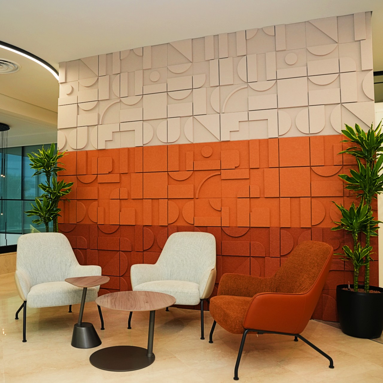 3D Decrasound PET acoustic wall panels in a modern office seating area, featuring geometric textured panels in neutral and terracotta colours to reduce noise and echo.