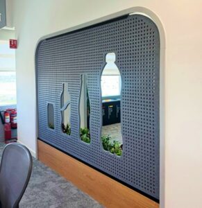 Decorative acoustic feature wall with custom cut-out shapes integrated into a workplace interior.
